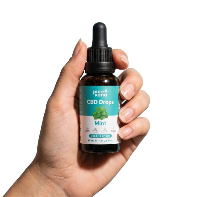 A hand holding a PureKana CBD Drops bottle